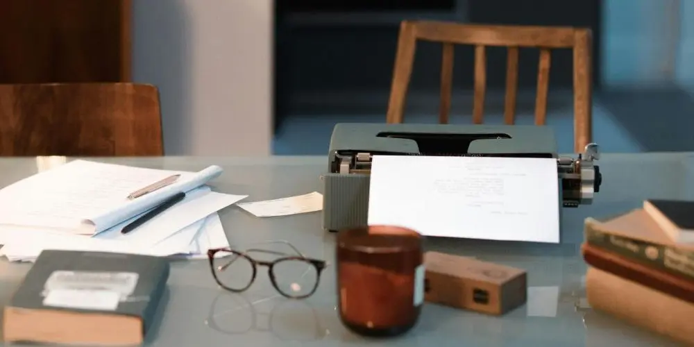 Bild zum Blogbeitrag "Schreibblockade lösen", zeigt Schreibtisch mit Schreibunterlagen.