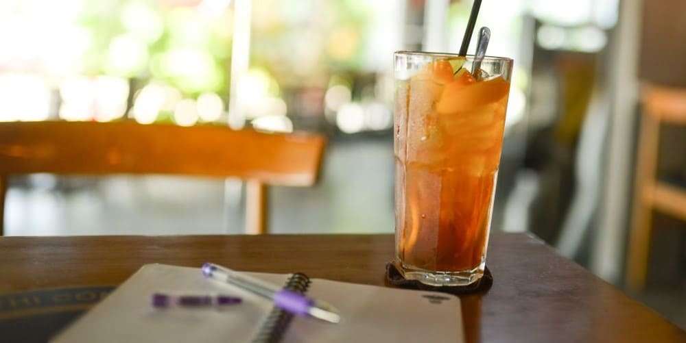 Bild zum Blogbeitrag Schreibimpulse fürs Sommerloch, zeigt ein Notizbuch und einen Drink.
