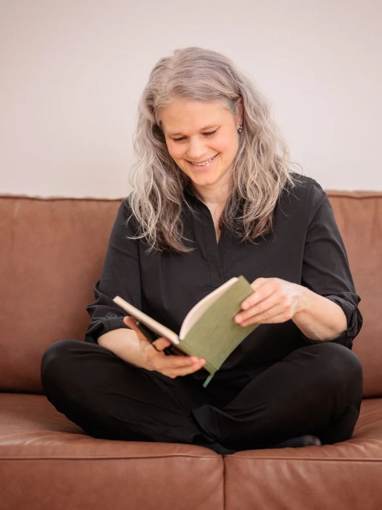 Schreibtrainerin Christine Kämmer leitet einen Workshop mit Notizbuch auf dem Sofa.